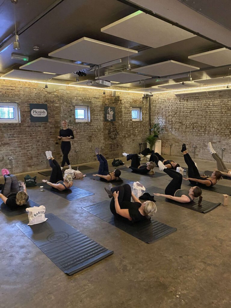 six people lying on backs with feet in the air during exercise class at Hel's pop-up