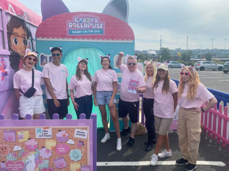 event staff manchester dressed in pink teeshirts in front of giant kids dollhouse part of an immersive roadshow experience